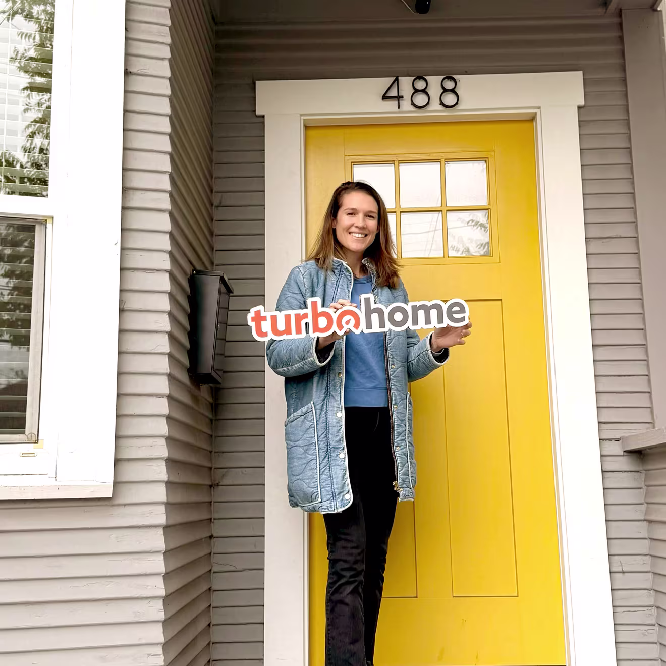 Customer holding a TurboHome sign in front of their new home